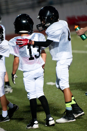 Young football boy putting his arm around his teammate