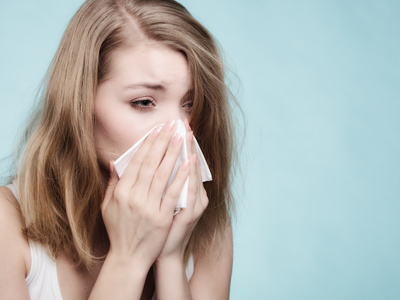 Sick girl sneezing in tissue