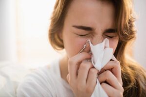 Woman blowing her nose into tissue