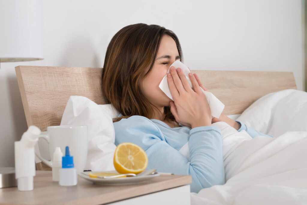 woman sneezing in bed