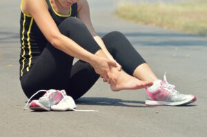 Woman sitting on ground in pain due to ankle injury