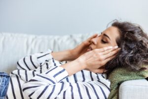 Young woman experiencing dizziness lying on a couch
