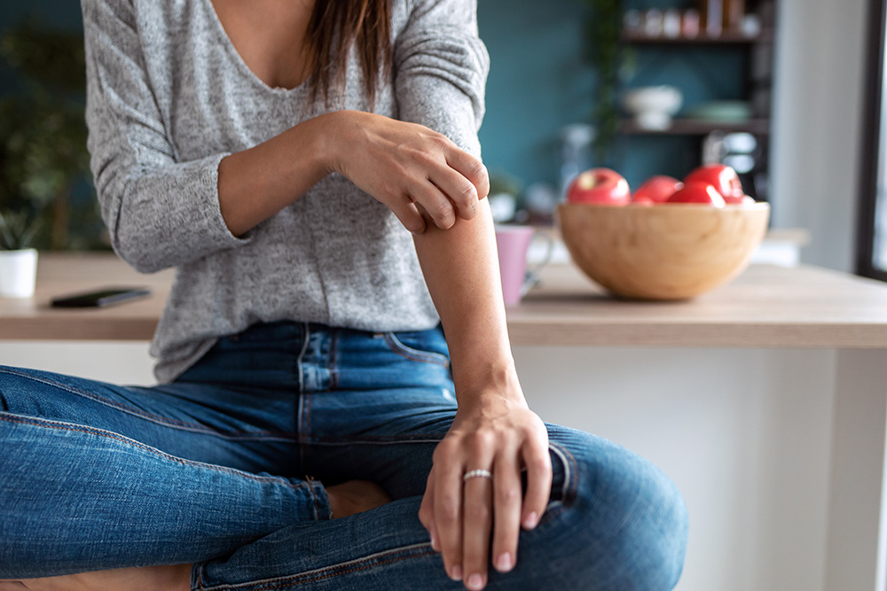 A woman scratches an irritation on her skin